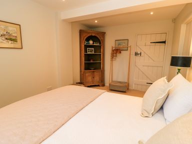 A bedroom with a bed pillow bookshelf wooden cupboard clothes rack door and lamp at The Elm Coach House in Chipping Norton