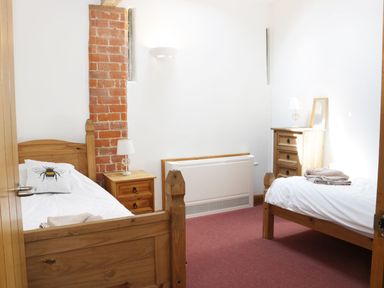 A bedroom with two single wooden beds a bedside table with a lamp a chest of drawers and a radiator at Woodside Cottage in Kerry