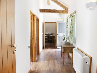 A hallway with wooden doors and beams a small wooden table with plants and a radiator at Woodside Cottage in Kerry