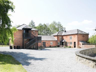 A gravel courtyard with brick buildings and outdoor seating at Woodside Cottage in Kerry