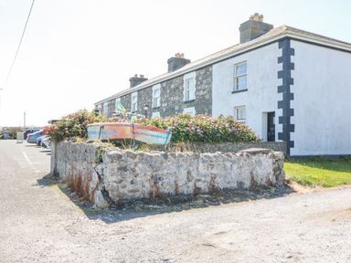 A stone and plaster house with a garden wall flowers and a small boat on the wall in Lonart near Killorglin County Kerry
