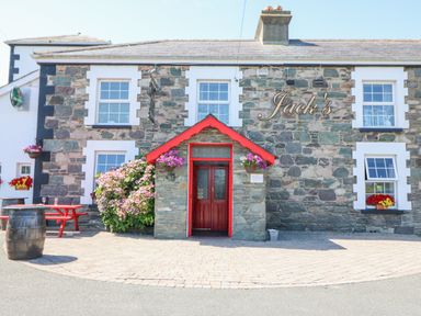Stone building with red entrance and flower baskets outside at Knockbrack Lonart near Killorglin County Kerry