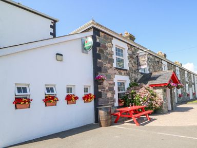 The exterior of a stone and white building with flower boxes under windows and a red picnic table outside at Knockbrack Lonart near Killorglin County Kerry