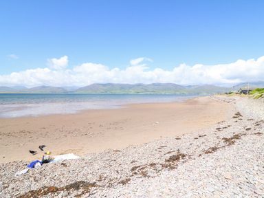 A beach with pebbles and sand by the sea with hills in the background at Knockbrack in Lonart near Killorglin County Kerry