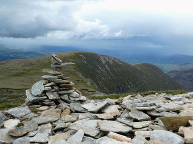 A pile of stacked stones on a mountain with hills and cloudy sky in the background at Knockbrack Lonart near Killorglin County Kerry