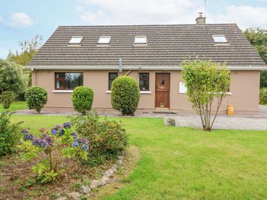A single-story house with a pitched roof and skylights surrounded by shrubs and a garden at Knockbrack Lonart near Killorglin County Kerry