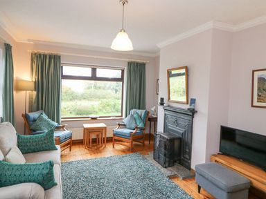 A living room with chairs a sofa a fireplace a television and a rug at Knockbrack in Lonart near Killorglin County Kerry