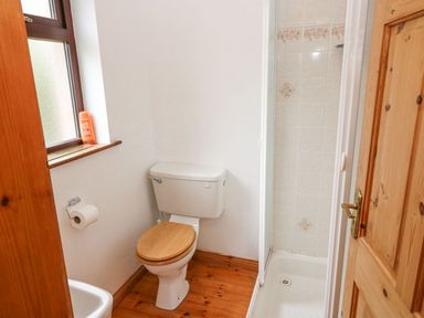 A bathroom with a toilet a shower and a window with a bottle on the sill at Knockbrack in Lonart near Killorglin County Kerry