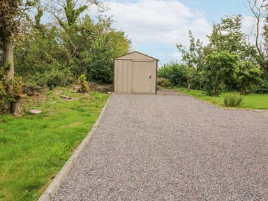 A gravel driveway leading to a small shed surrounded by grass and trees at Knockbrack Lonart near Killorglin County Kerry
