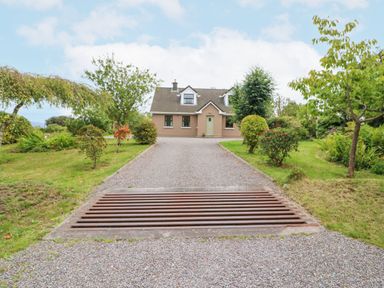 A house with a gravel driveway and trees on both sides at Knockbrack in Lonart near Killorglin County Kerry