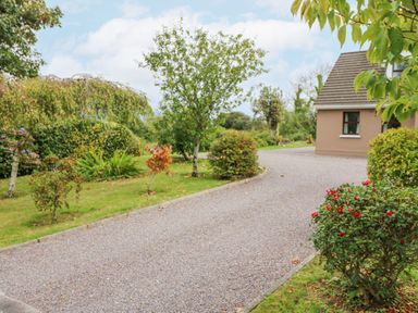 A gravel driveway surrounded by trees and bushes next to a house at Knockbrack in Lonart near Killorglin County Kerry