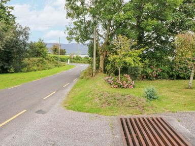 A road with yellow lines beside a grassy area with trees and flowers at Knockbrack in Lonart near Killorglin County Kerry