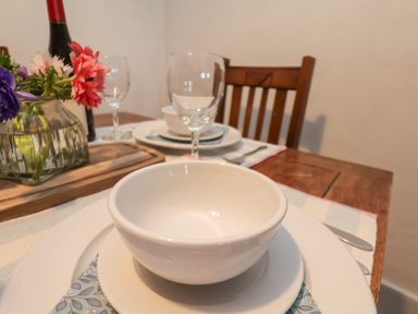 A dining table set with white bowls plates wine glasses and a vase of flowers at Field View in Ruswarp