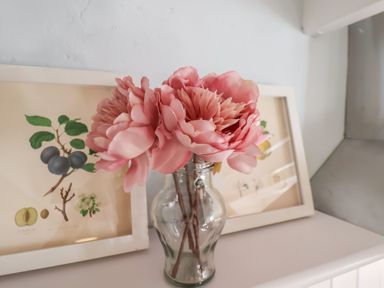 A vase with pink flowers on a white surface with framed botanical prints in the background at Field View in Ruswarp