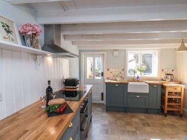 A kitchen with wooden countertops a stove a sink and a door at Field View in Ruswarp