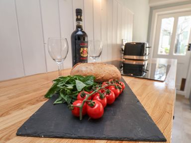 A kitchen counter with vine tomatoes bread basil a bottle of wine and two wine glasses at Field View in Ruswarp