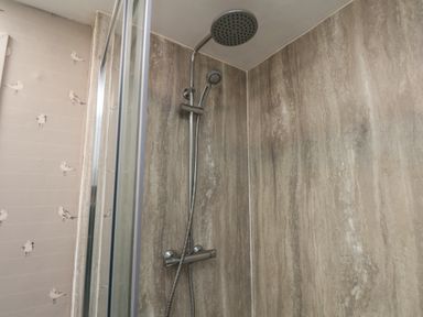 A shower with two showerheads and marble patterned walls at Field View in Ruswarp