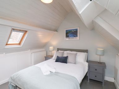 A bedroom with a bed and bedside tables under a sloped ceiling at Field View in Ruswarp