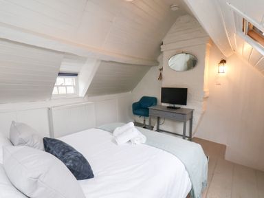 A bedroom with a bed pillows and towels a small desk with a television and a blue chair at Field View in Ruswarp