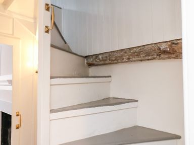 A staircase with white painted steps and a wooden handrail at Field View in Ruswarp