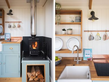 A kitchen corner with a wood stove and stacked firewood next to a sink with a faucet and shelves holding plates and plants at Stargazer in St Erme near Truro