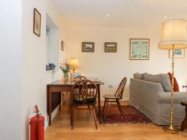 A dining table with chairs and a lamp next to a sofa with cushions and a rug in a living room at The Wheelhouse Beacon near Yarcombe
