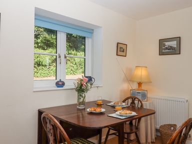 A dining area with a wooden table set with plates of croissants and glasses of orange juice next to a window at The Wheelhouse Beacon near Yarcombe