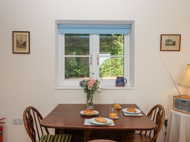 A dining table with croissants and orange juice by a window with blue blind at The Wheelhouse Beacon near Yarcombe