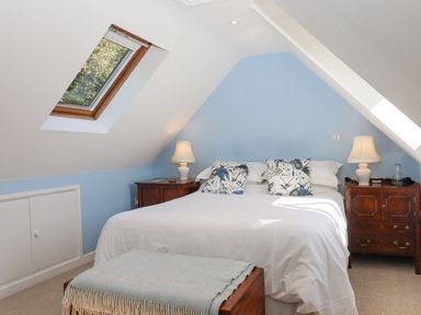 A bedroom with a bed two bedside tables with lamps and skylight windows at The Wheelhouse Beacon near Yarcombe