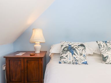 A bedroom with a wooden nightstand lamp and pillows on a bed at The Wheelhouse Beacon near Yarcombe