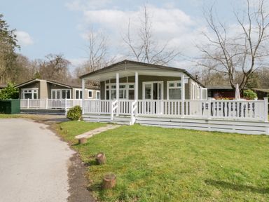 Two single-story holiday lodges with white railings and a green lawn at Cosy Corner in White Cross Bay near Troutbeck Bridge
