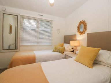 A bedroom with two beds and a mirror at Cosy Corner White Cross Bay near Troutbeck Bridge