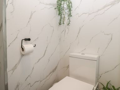 A bathroom with a toilet and toilet paper holder at Cosy Corner near White Cross Bay