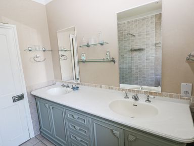 A bathroom with a double sink vanity and large mirrors at Hereford House in Tenby