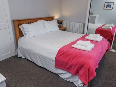 A bedroom with a bed and mirror at Kennie Cottage in Seahouses