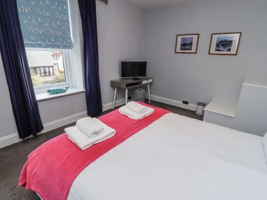 A bedroom with a bed and television at Kennie Cottage in Seahouses