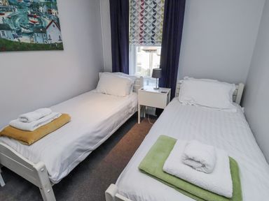 A bedroom with two single beds and a bedside table at Kennie Cottage, Seahouses