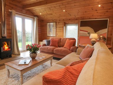 A living room with sofas cushions a coffee table with flowers a fireplace and wall art at Artisan Lodge in Longridge