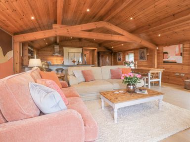 A living room with wooden ceiling and walls with two sofas and a wooden coffee table with flowers at Artisan Lodge in Longridge