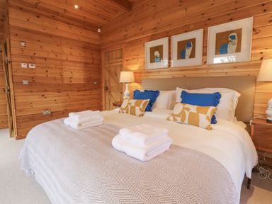 A bedroom with a large bed with blue and yellow pillows and folded towels on a blanket at Artisan Lodge in Longridge