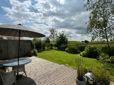 A garden with a patio table and umbrella next to a shed and green lawn at Artisan Lodge in Longridge