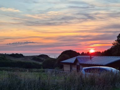 A sunset over hills with a small house and a car in the foreground at Bay in Ilfracombe