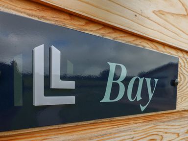 A close up of a sign with the word Bay on a wooden wall at Bay Ilfracombe