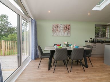 A dining area with a table set for six and a kitchen in the background at Bay in Ilfracombe