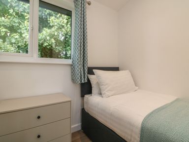 A bedroom with a single bed next to a window and a three drawer dresser at Bay in Ilfracombe