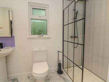 A bathroom with a toilet sink window and a glass shower enclosure at Bay in Ilfracombe