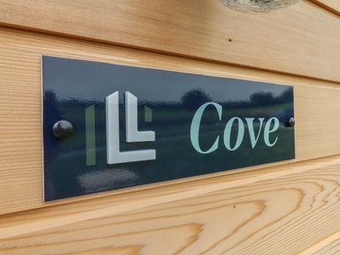 A close up of a sign reading Cove mounted on a wooden wall at Cove Lodge in Ilfracombe