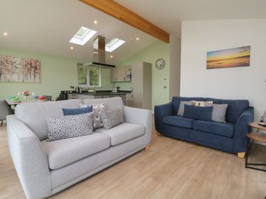 A living room with two sofas and a kitchen in the background at Cove Lodge in Ilfracombe