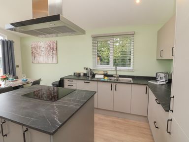 A kitchen with black countertops cabinets a sink toaster and a dining table at Cove Lodge Ilfracombe