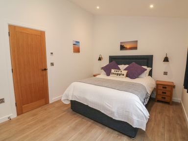 A bedroom with a bed with pillows and two bedside tables at Cove Lodge in Ilfracombe